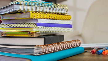hromada notebooků, Barevné notebooky, spirálové notebooky, dřevěný stůl, zpátky do školy, tužky, školní potřeby, studijní materiály, vzdělání, Organizace stolu, Barevné papírnictví