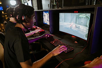man playing computer game, focused gamers, high-performance computers, cyber cafe, online gaming session, gaming headset, red keyboard, gaming mouse, computer monitor, gaming environment, intense gaming