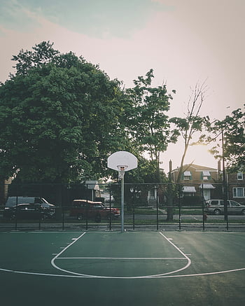 basketball park, serene basketball court, leafy neighborhood, sunset, front view, outdoor basketball, residential area, trees, sports court, community park, evening light