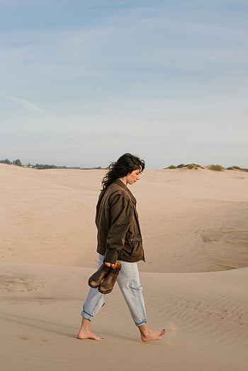 woman walking, sand, barefoot, carrying shoes, sandy dunes, clear blue sky, outdoor, nature, desert, casual style, relaxed mood