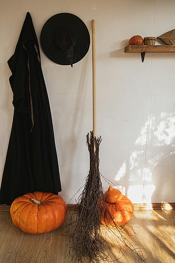Halloween decor, orange pumpkin, black witch costume, witch broom, witch hat, autumn celebrations, indoor Halloween, Halloween-themed decor, pumpkins indoors, Halloween decorations, witch costume