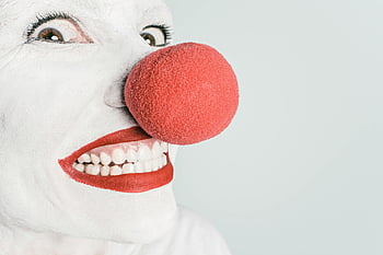 clown, red nose, pink lipstick, smiling person, bright close-up, humor, joy, clown makeup, white face paint, clown face, red lips