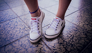 white sneakers, low-top sneakers, textured tiled surface, white low-top sneakers, pair of sneakers, white shoes, casual footwear, sneaker style, white canvas shoes, sneaker fashion, white athletic shoes