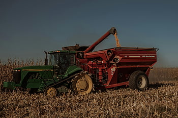 green tractor, red combine, harvesting corn, rural farmland, heavy equipment, cropland, agricultural machinery, farm vehicle, John Deere, crop harvesting, cornfield