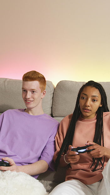 adolescenti che giocano ai videogiochi, Accogliente configurazione di divano, Gaming interno, Controller di videogiochi, adolescenti rilassati, sessione di gioco, intrattenimento interno, GIOCO CASUALE, amici che giocano insieme, accogliente soggiorno, configurazione del videogioco