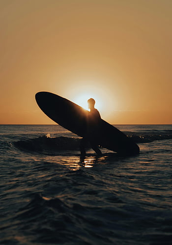Muž s surfem, pláž západ slunce, Silueta Surfer, Sunset Beach Scéna, přenášení surfování, klidná pláž, západ slunce oceánu, plážové vlny, slunce silueta, Ve večerních plážích, Surfboard při západu slunce