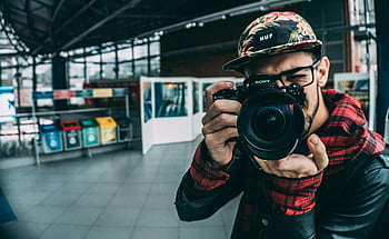 man holding DSLR camera, young adult photographer, indoor photography, modern photography, DSLR camera, photographer indoors, photography equipment, casual photographer, urban photography, photography hobby, photo enthusiast