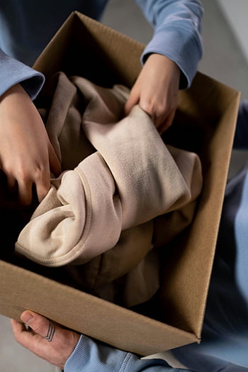 donazioni di beneficenza, donazione di abbigliamento, Mani di smistamento dei vestiti, scatola di cartone, scatola marrone, mani ravvicinate, vestiti piegati, scatola di donazione, scatola della persona, Box di beneficenza, scatola di abbigliamento