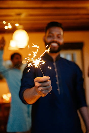 homme tenant sparkler, célébration intérieure festive, Ambiance chaleureuse, moment joyeux, cierge scintillant brillant, photo en gros plan, célébration intérieure, Célébration de cler, atmosphère festive, Homme avec du cierge magique, Sparkin intérieur