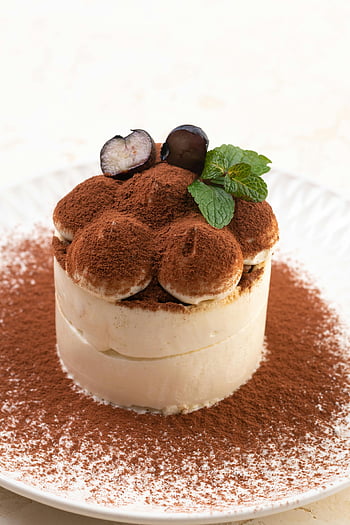 tiramisu cake, close-up shot, cocoa powder, dessert, mint garnish, layered cake, sweet treat, Italian dessert, cream topping, plated dessert, food photography
