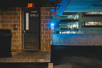 exit signboard, brick building, parking garage, level 3, dimly lit, emergency lights, night scene, exit signs, garage exit, building exterior, urban night