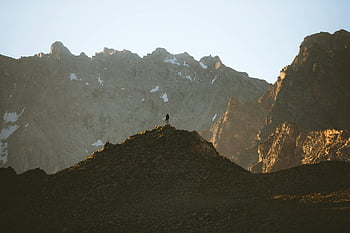 Persona de pie cerca de las montañas, figura solitaria, cima de la montaña, Karachay-Cherkessia, Rusia, picos resistentes, telón de fondo majestuoso, aventura al aire libre, paisaje natural, vista panorámica, destino de senderismo