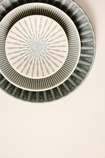 ceramic saucers, ceramic plates, stacked plates, patterned ceramic, overhead shot, neutral background, ceramic dishware, stacked ceramics, patterned plates, ceramic tableware, neutral backdrop