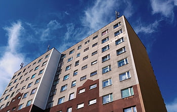 brown concrete building, modern urban apartment, low angle view, cloudy blue sky, urban architecture, apartment building, modern building, cityscape, urban living, blue sky background, building exterior