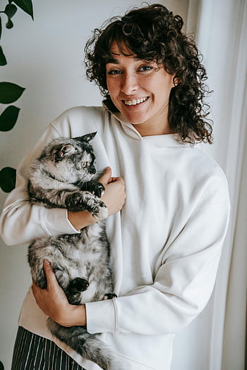 smiling woman, domestic cat, embracing cat, fluffy gray cat, joyful moment, indoors, home setting, woman and cat, pet owner, casual outfit, natural light