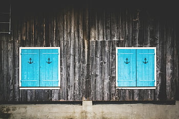 brown wooden frame, turquoise shuttered windows, anchor designs, charming wooden facade, wooden wall, blue shutters, rustic building, nautical theme, window shutters, wooden exterior, anchor decor