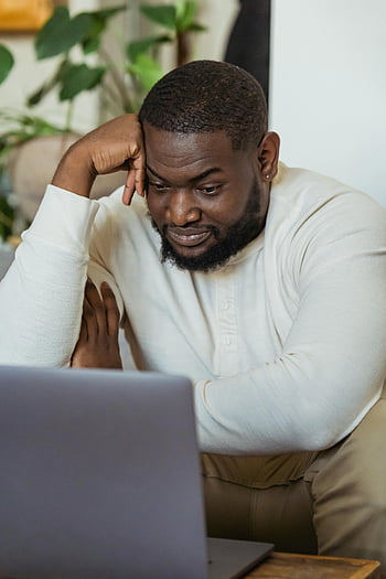 man, white sweater, laptop computer, browsing, at home, smiling, comfortable, indoor setting, focused, casual work, technology use
