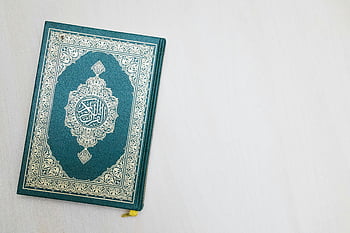 Al Quran, white surface, intricate Arabic design, spiritual essence, holy book, Islamic text, religious book, Quran cover, white background, religious art, spiritual book