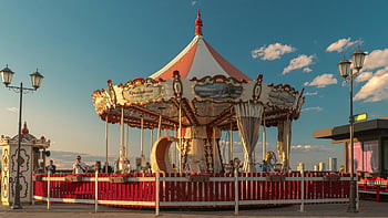 retro merry-go-round, vintage carousel, boardwalk, sunlit, blue sky, charming, outdoor, amusement park, seaside, fairground, entertainment