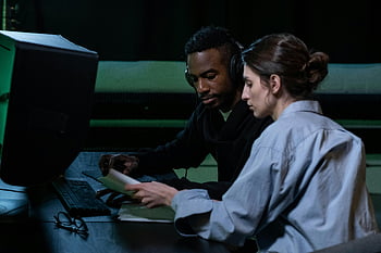 働いている男と女性、 協力している同僚、 集中編集、 コンピューター作業、 効果的なコラボレーション、 チームワーク、 オフィス環境、 プロの環境、 共有タスク、 ドキュメントレビュー、 ヘッドセットの使用