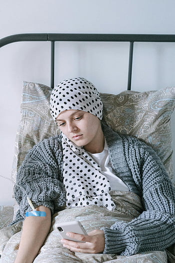 woman, polka dots headscarf, hospital bed, smartphone, cancer treatment, patient, medical care, recovery, healthcare, bedridden, technology use