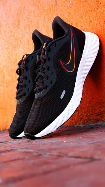 Nike running shoes, black running shoes, orange swoosh, athletic shoes, close-up shoes, orange wall, Nike sneakers, black sneakers, white soles, sports footwear, shoe details