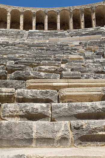 ancient amphitheater, stone stairs, architectural details, low angle view, amphitheater steps, historical architecture, arched structures, classical architecture, blue sky backdrop