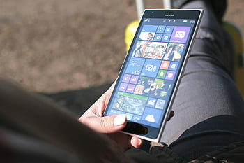 Nokia Windows Phone, black Nokia phone, woman holding phone, touchscreen interface, outdoor photo, Nokia smartphone, Windows operating system, close-up photo, mobile device, smartphone user, outdoor technology