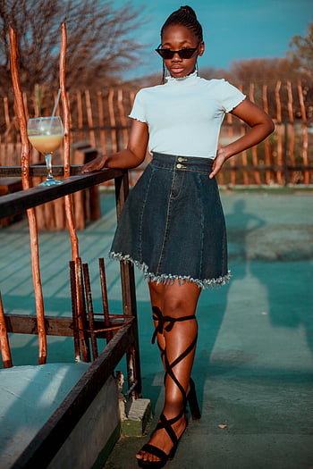 foco seletivo, mulher em pé, camisa branca, Saia de jeans azul, corrimão de madeira, oculos escuros, roupa casual, terraço de madeira, moda, exterior, posando