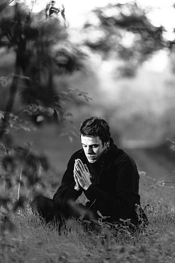 fotografia in scala di grigi, uomo seduto, campo d'erba, meditazione, Mani in preghiera, bianco e nero, Meditazione all'aperto, scena pacifica, ambiente naturale, Posa contemplativa, ambiente sereno