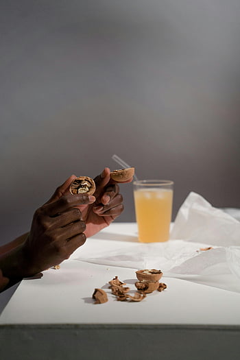 hands cracking walnuts, broken walnuts, close-up of hands, walnuts and juice, nut cracking, hands holding broken nuts, glass of juice, table, snack time.