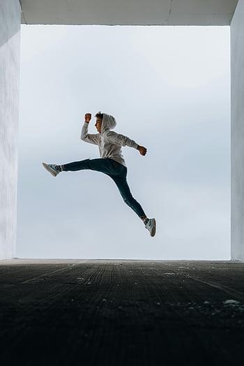 boy, hoodie, jumping, vertical jump, outdoors, athleticism, energy, high jump, casual wear, urban setting, dynamic movement