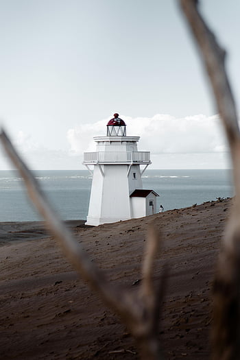 white lighthouse, sandy shore, calm ocean, serene scene, guiding ships, ocean waves, coastal landscape, beach scenery, lighthouse beacon, maritime navigation, seaside view