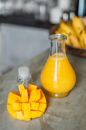 mangový džus, skleněná láhev, žlutá kapalina, nakrájené mango, tropické atmosféry, čerstvě vymačkané, stůl, ovoce, zdravý nápoj, letní občerstvení, přírodní šťávy