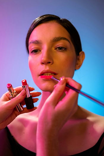 makeup artist, applying lipstick, beautiful woman, close-up, vibrant lighting, lipstick application, makeup process, professional makeup, beauty photography, woman's lips, makeup tools