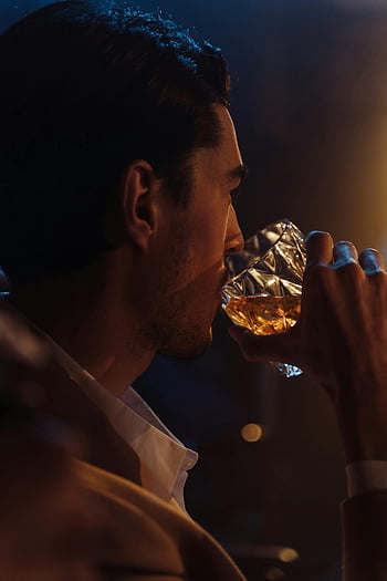 man drinking whisky, dimly-lit bar, elegant profile, relaxation, mood, alcoholic drink, glass of whisky, man enjoying drink, bar atmosphere, nighttime setting, sophisticated man
