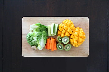 beige wooden chopping board, fresh fruits, vegetables, healthy salad, wooden board, kiwi slices, mango cubes, carrot sticks, cucumber slices, lettuce leaves, salad preparation
