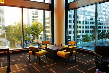 hotel lounge, yellow chairs, cityscape view, large windows, contemporary design, coffee table, modern furniture, indoor seating, urban view, comfortable seating, hotel interior