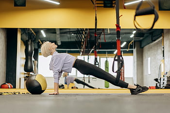 kvinne strekker seg, Pilates trening, medisin ball, moderne treningsstudio, kvinnelig idrettsutøver, tøyningsøvelse, treningsstudioinnstilling, treningsøkt, trene ballen, innendørs trening, treningsutstyr