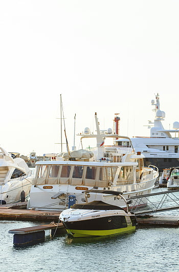 white yacht, wooden dock, luxury yachts, vibrant marina, sunny day, docked boats, marina scene, yacht parking, watercraft, dockside view, nautical setting