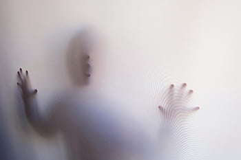 person behind curtain, eerie silhouette, mysterious atmosphere, white curtain, pressing hands, shadow figure, ghostly appearance, translucent effect, blurred image, spooky scene, hidden person