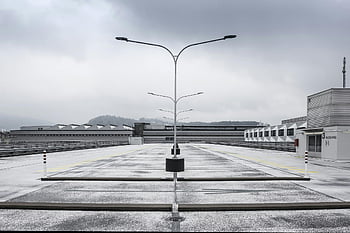 cityscape, rooftop parking, streetlights, cloudy day, winter scene, deserted area, urban view, building exterior, industrial area, overcast sky, city buildings
