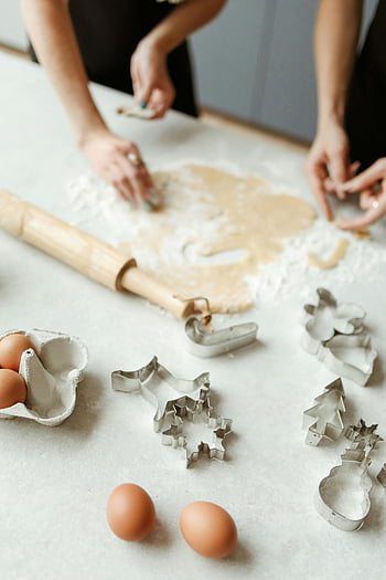 women preparing dough, table, home cookie baking, family hands, utensils, bonding moment, rolling pin, cookie cutters, eggs, flour, dough rolling