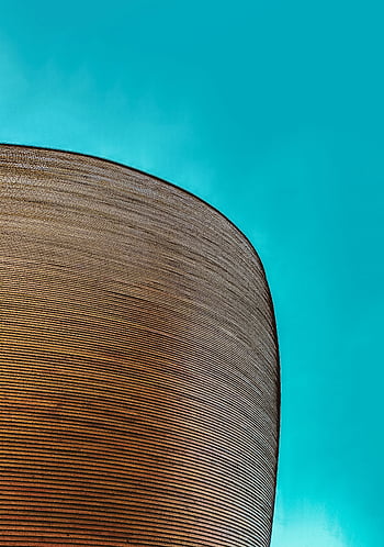 Helsinki architecture, bold design, vivid blue sky, round structure, brown textile, modern building, architectural detail, Finland landmark, curved facade, urban skyline, contemporary design