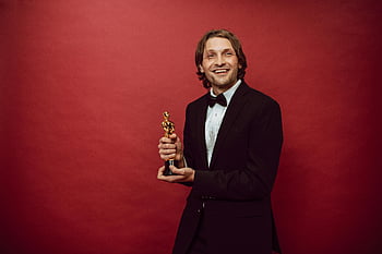 hrdý herec, držení trofeje, šťastný muž, oblek, Červené pozadí, Oslava úspěchu, Oscar Award, portrét, úspěch, předávání cen, usmívající se