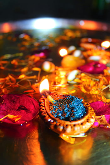 Diwali, lighted candles, floating diyas, petals in water, festive ambiance, close-up shot, bright lights, Diwali decorations, water surface, colorful petals, traditional festival