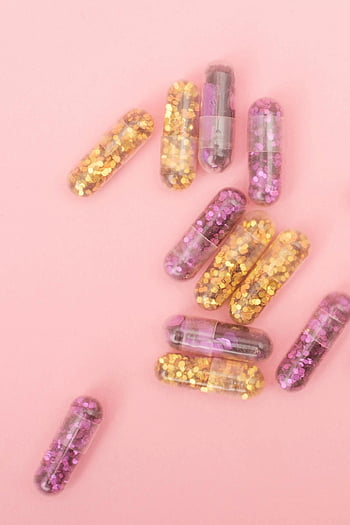 Glitzerkapseln, leuchtend lila, goldener Glitzer, Buntes Glitzer, Feste Themen, kreative Themen, rosa Oberfläche, Nahaufnahmefoto, Dekorative Kapseln, Partydekorationen, Bastelmaterial