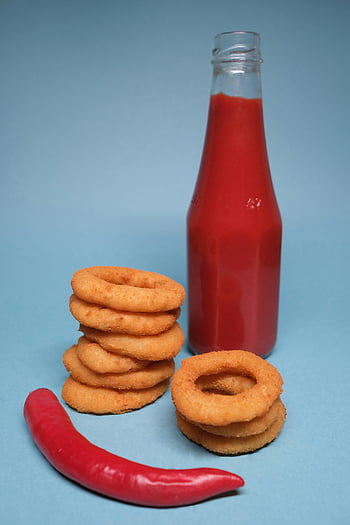 chili pepper, ketchup, onion rings, blue background, spicy red sauce, golden onion rings, red chili pepper, food photography, appetizer, snack, condiment bottle