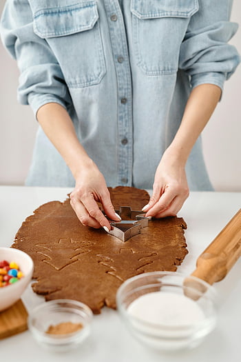 cookie cutter, gingerbread dough, Christmas cookies, close-up hands, baking, festive baking, holiday cookies, dough cutting, cookie preparation, kitchen activity, gingerbread man
