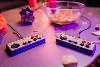 Retro-Spiele, klassische 8-Bit-Controller, Snacks, Grauer Tisch, Zauberwürfel, Entspannte Einstellung, Vintage-Controller, Gaming-Szene, 8-Bit-Controller, Schüssel Snacks, lila Beleuchtung